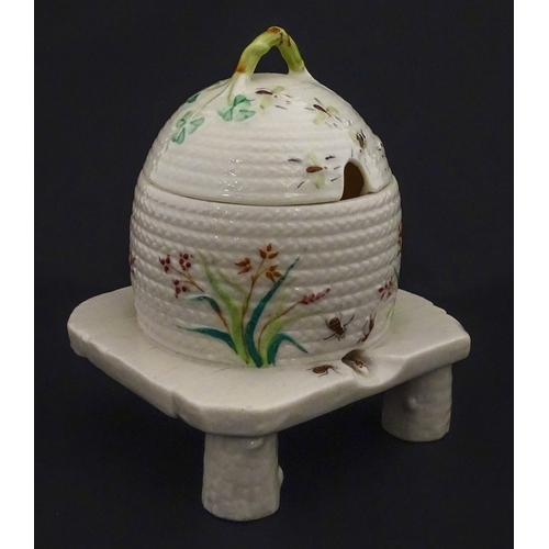 94 - A Belleek honey pot on stand of skep / beehive form decorated with bees, flowers and shamrocks. Rais... 