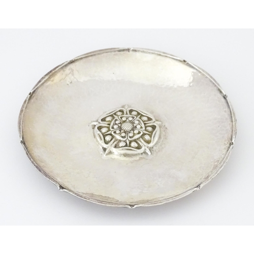 501 - An Arts & Crafts silver dish of circular form with hammered decoration and centre Tudor rose motif, ... 
