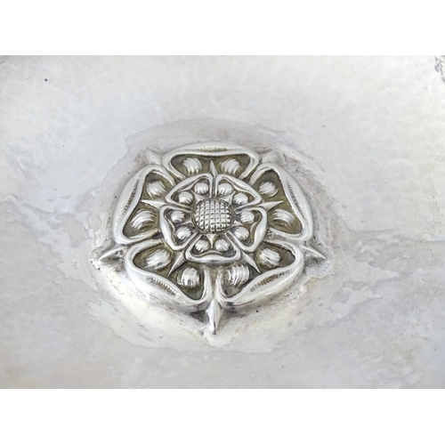 501 - An Arts & Crafts silver dish of circular form with hammered decoration and centre Tudor rose motif, ... 