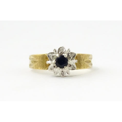 624 - A 9ct gold ring set with central sapphire bordered by diamonds. Ring size approx. L 1/2