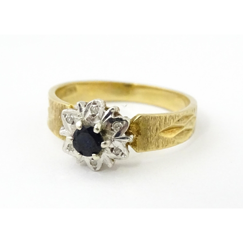624 - A 9ct gold ring set with central sapphire bordered by diamonds. Ring size approx. L 1/2