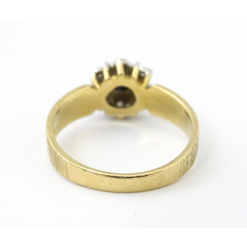624 - A 9ct gold ring set with central sapphire bordered by diamonds. Ring size approx. L 1/2