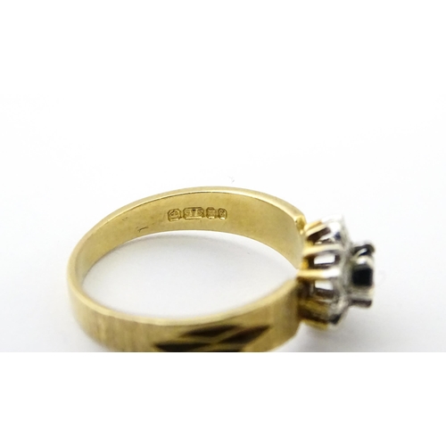 624 - A 9ct gold ring set with central sapphire bordered by diamonds. Ring size approx. L 1/2