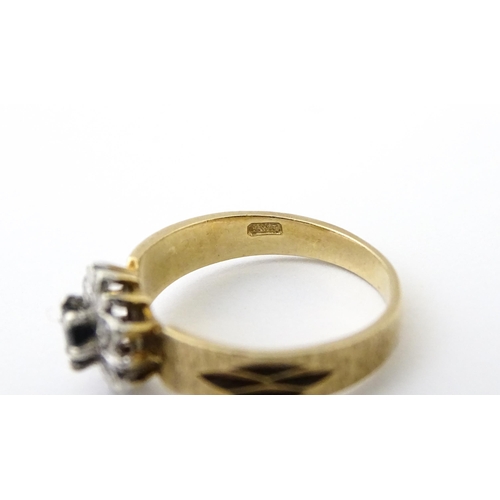 624 - A 9ct gold ring set with central sapphire bordered by diamonds. Ring size approx. L 1/2