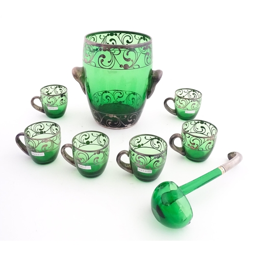 315 - A Spanish green glass punch bowl with ladle and six punch cups with silvered overlay detail. Marked ... 