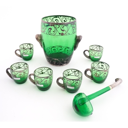 315 - A Spanish green glass punch bowl with ladle and six punch cups with silvered overlay detail. Marked ... 