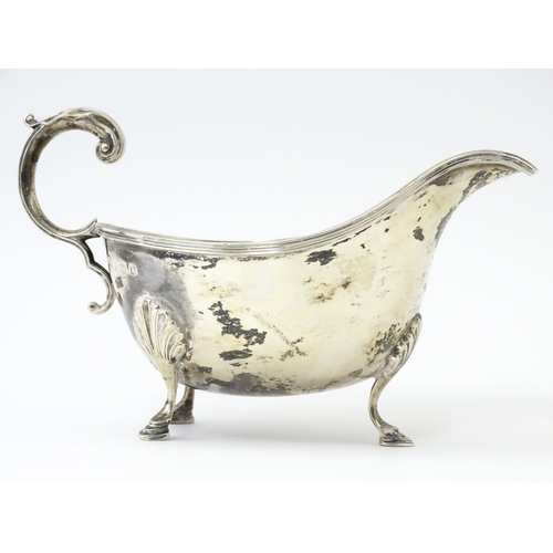 325 - A silver sauce boat raised on three feet with a scroll handle, hallmarked Sheffield 1930, maker Will... 