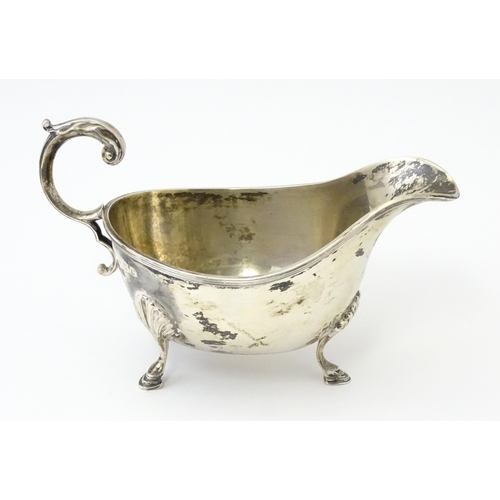 325 - A silver sauce boat raised on three feet with a scroll handle, hallmarked Sheffield 1930, maker Will... 