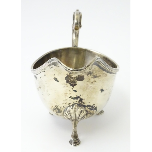 325 - A silver sauce boat raised on three feet with a scroll handle, hallmarked Sheffield 1930, maker Will... 