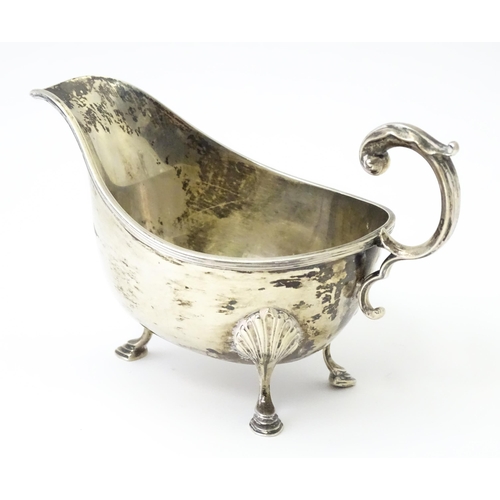 325 - A silver sauce boat raised on three feet with a scroll handle, hallmarked Sheffield 1930, maker Will... 