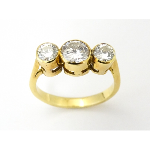 810 - An 18ct gold ring set with trio of diamonds, the central diamond approx 6mm diameter flanked by two ... 