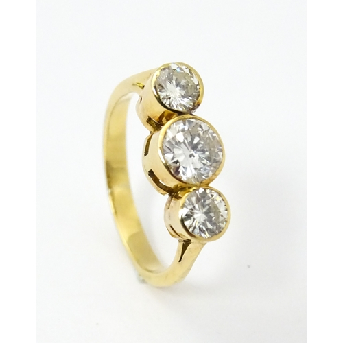 810 - An 18ct gold ring set with trio of diamonds, the central diamond approx 6mm diameter flanked by two ... 