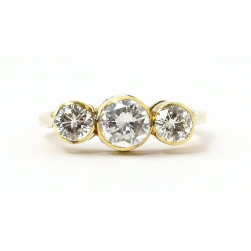 810 - An 18ct gold ring set with trio of diamonds, the central diamond approx 6mm diameter flanked by two ... 