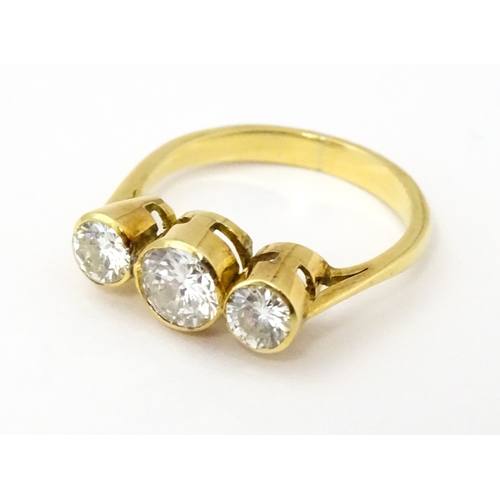 810 - An 18ct gold ring set with trio of diamonds, the central diamond approx 6mm diameter flanked by two ... 