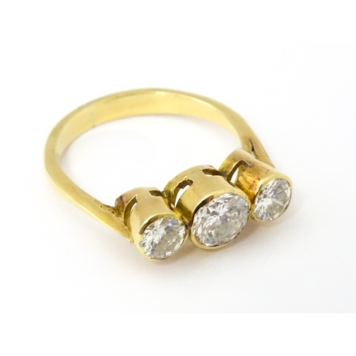 810 - An 18ct gold ring set with trio of diamonds, the central diamond approx 6mm diameter flanked by two ... 
