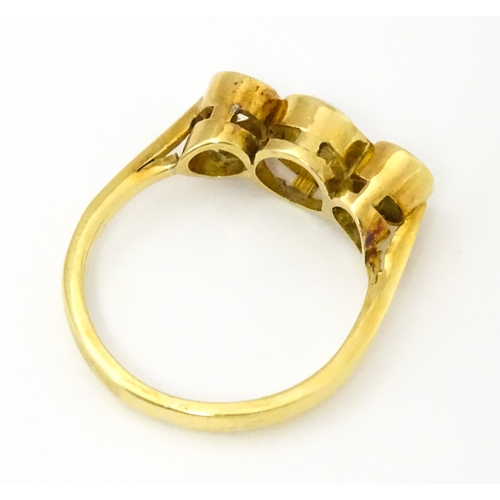 810 - An 18ct gold ring set with trio of diamonds, the central diamond approx 6mm diameter flanked by two ... 