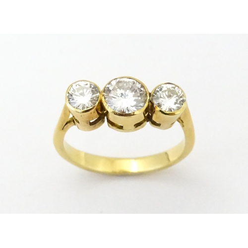 810 - An 18ct gold ring set with trio of diamonds, the central diamond approx 6mm diameter flanked by two ... 