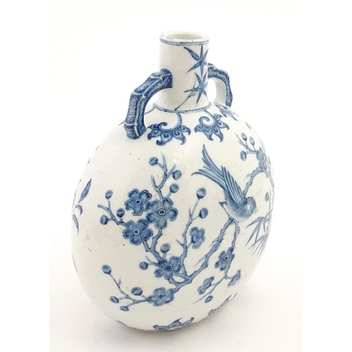 65 - A Chinese blue and white twin handled moon vase decorated with a bird perched on a branch. Approx. 9... 