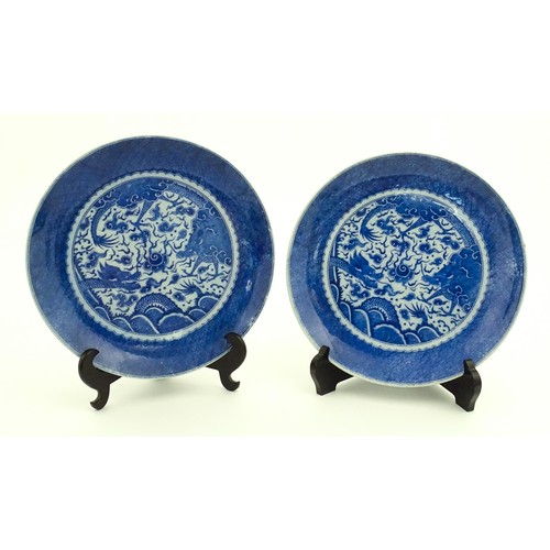 72 - A pair of Chinese blue and white chargers decorated with dragons and a flaming pearl amongst stylise... 