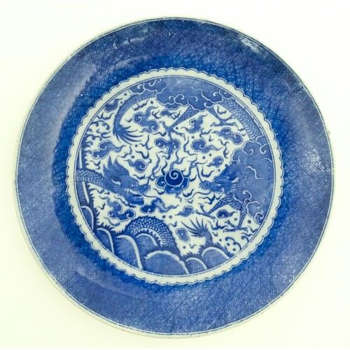 72 - A pair of Chinese blue and white chargers decorated with dragons and a flaming pearl amongst stylise... 