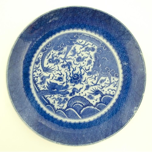 72 - A pair of Chinese blue and white chargers decorated with dragons and a flaming pearl amongst stylise... 