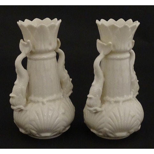 110 - A pair of Belleek dolphin spill vases with twin fish handles and shell detail to base. Marked with S... 