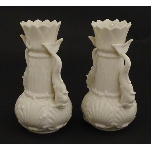 110 - A pair of Belleek dolphin spill vases with twin fish handles and shell detail to base. Marked with S... 
