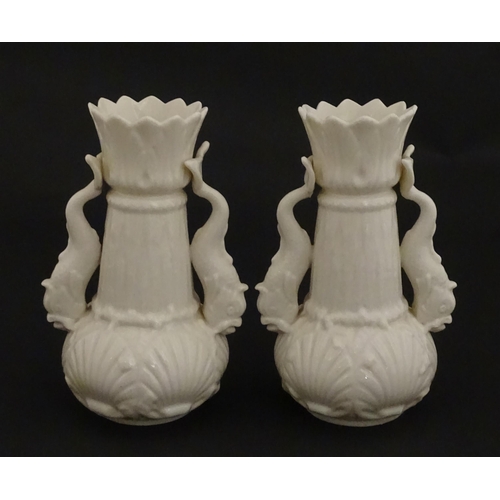 110 - A pair of Belleek dolphin spill vases with twin fish handles and shell detail to base. Marked with S... 