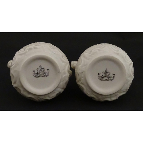 110 - A pair of Belleek dolphin spill vases with twin fish handles and shell detail to base. Marked with S... 