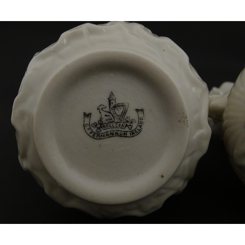 110 - A pair of Belleek dolphin spill vases with twin fish handles and shell detail to base. Marked with S... 