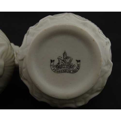 110 - A pair of Belleek dolphin spill vases with twin fish handles and shell detail to base. Marked with S... 