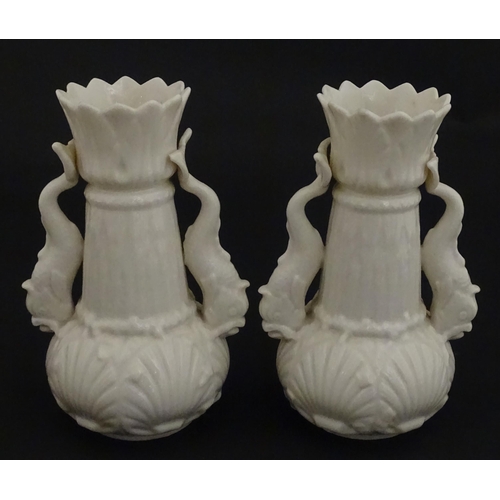 110 - A pair of Belleek dolphin spill vases with twin fish handles and shell detail to base. Marked with S... 