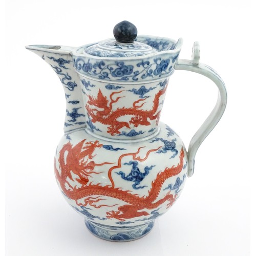 13 - A Chinese blue, white and iron red wine ewer decorated with dragons and stylised clouds. Character m... 