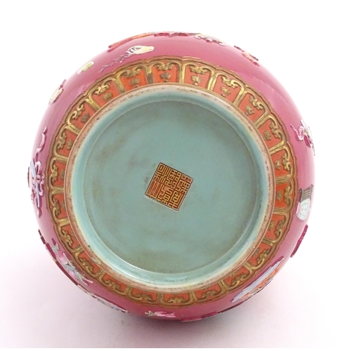 48 - A Chinese famille rose vase with twin elephant mask handles decorated in relief with vases, flowers ... 