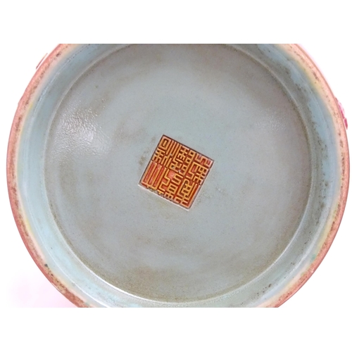 48 - A Chinese famille rose vase with twin elephant mask handles decorated in relief with vases, flowers ... 