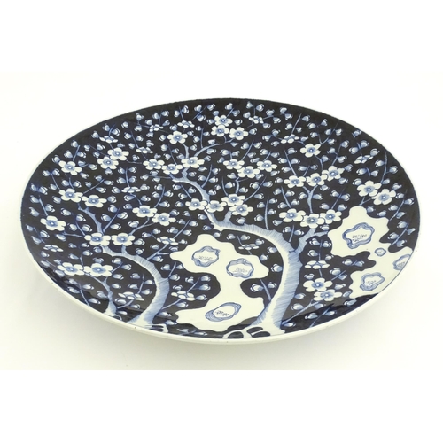 63A - A large Chinese blue and white charger decorated with prunus blossom and taihu rocks, with brushwork... 
