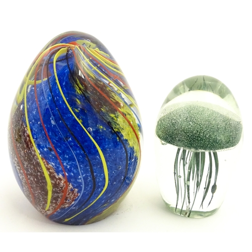 323 - An art glass paperweight of egg form with abstract coloured swirl detail. Together with a smaller gl... 
