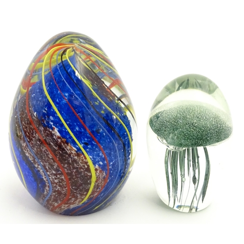 323 - An art glass paperweight of egg form with abstract coloured swirl detail. Together with a smaller gl... 