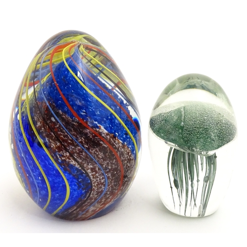 323 - An art glass paperweight of egg form with abstract coloured swirl detail. Together with a smaller gl... 