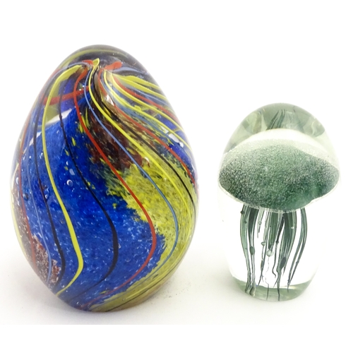 323 - An art glass paperweight of egg form with abstract coloured swirl detail. Together with a smaller gl... 