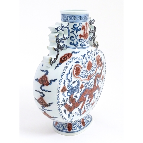 10 - A Chinese red, blue and white vase with scrolling twin handles, decorated with a dragon amongst styl... 
