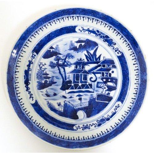 34 - A Chinese export blue and white plate decorated with a river landscape with figures, pagodas, etc. T... 