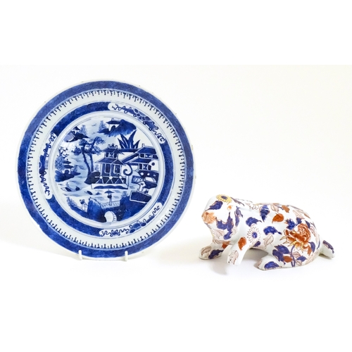 34 - A Chinese export blue and white plate decorated with a river landscape with figures, pagodas, etc. T... 