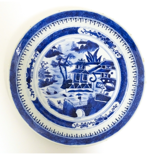 34 - A Chinese export blue and white plate decorated with a river landscape with figures, pagodas, etc. T... 
