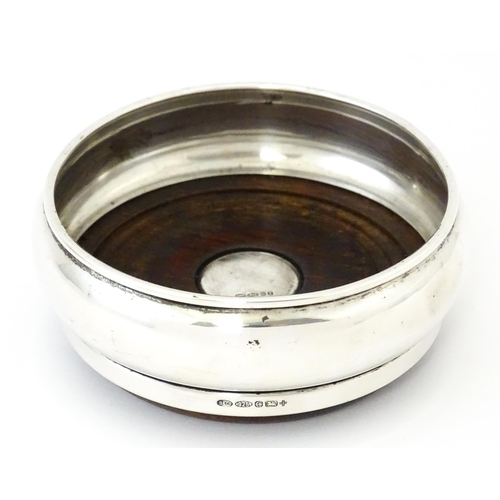 354 - A silver bottle coaster with turned wooden base, hallmarked Birmingham 1999, maker W I Broadway & Co... 