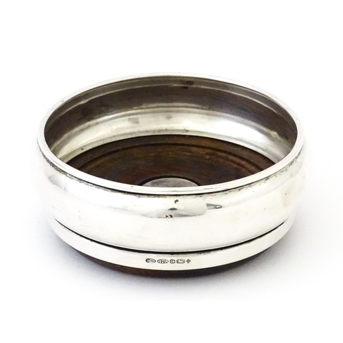 354 - A silver bottle coaster with turned wooden base, hallmarked Birmingham 1999, maker W I Broadway & Co... 