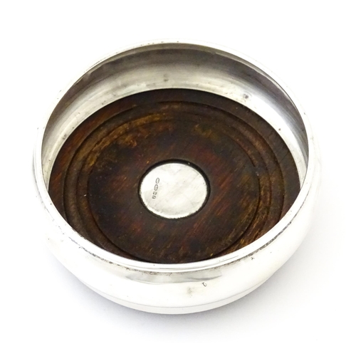 354 - A silver bottle coaster with turned wooden base, hallmarked Birmingham 1999, maker W I Broadway & Co... 