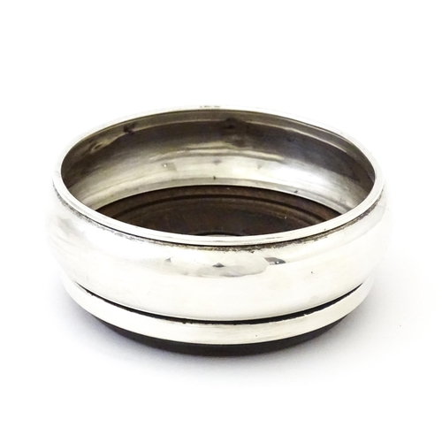 354 - A silver bottle coaster with turned wooden base, hallmarked Birmingham 1999, maker W I Broadway & Co... 