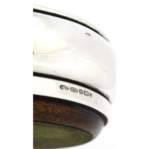 354 - A silver bottle coaster with turned wooden base, hallmarked Birmingham 1999, maker W I Broadway & Co... 