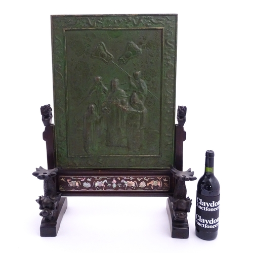 1262 - A Chinese table screen with cast green painted panel having relief decoration depicting an Imperial ... 